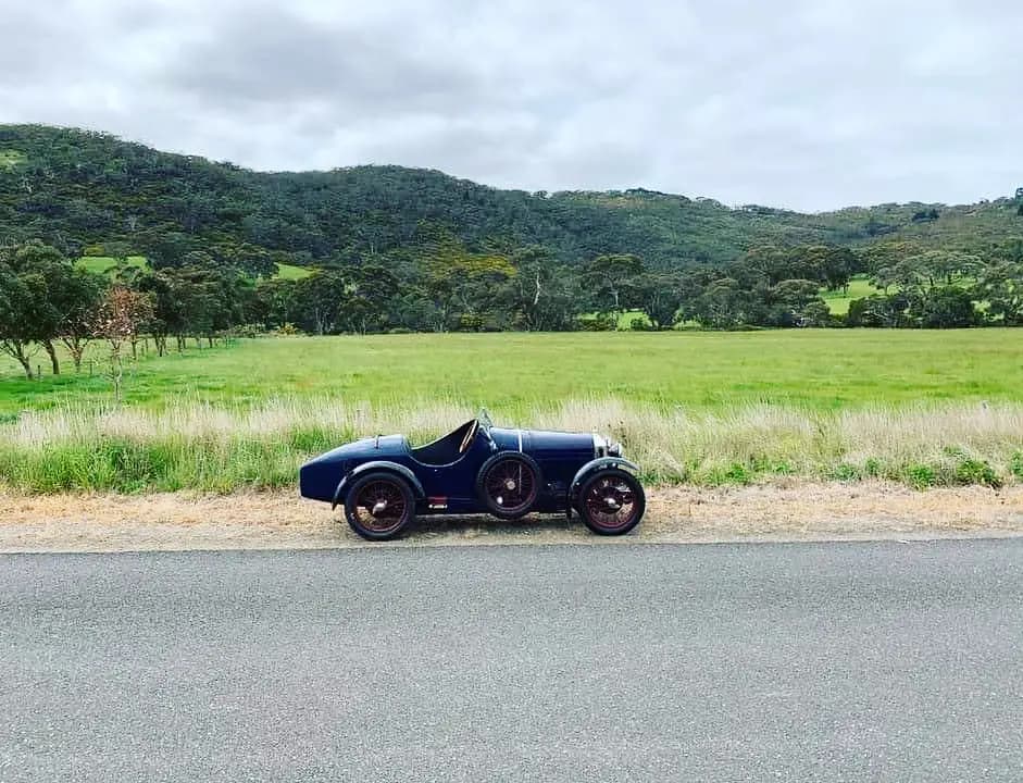A blue vintage car beside a country road, from the Mitchell Automotive family story
