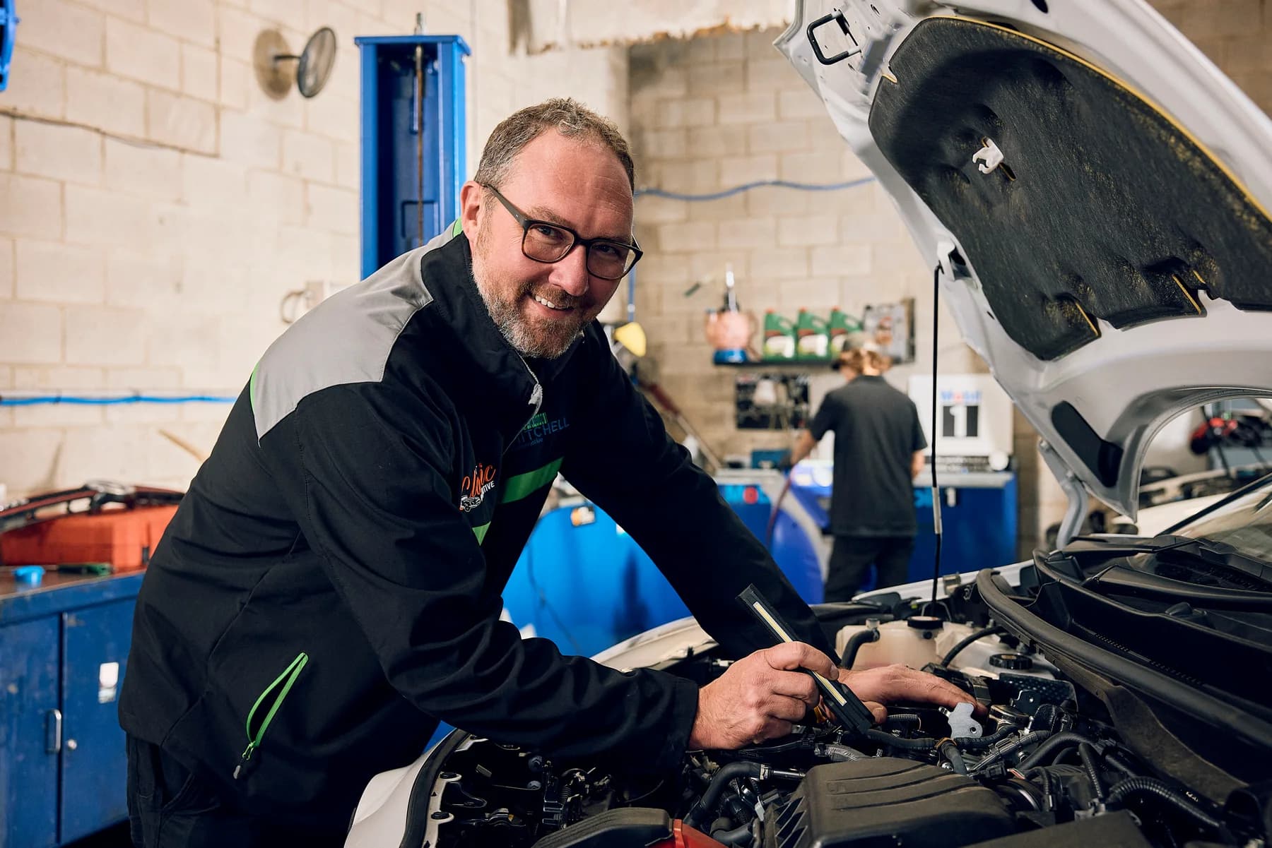 A smiling Mitchell Automotive mechanic working on a European car in the Edwardstown workshop