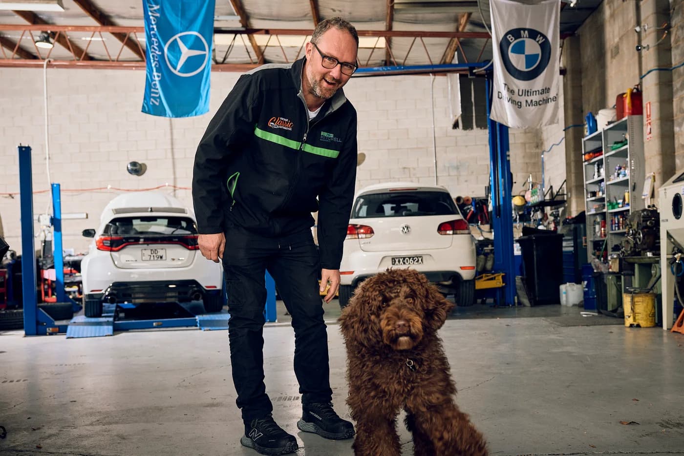 Mr Winston, the curly-haired brown workshop dog, with a member of Mitchell Automotive in Edwardstown